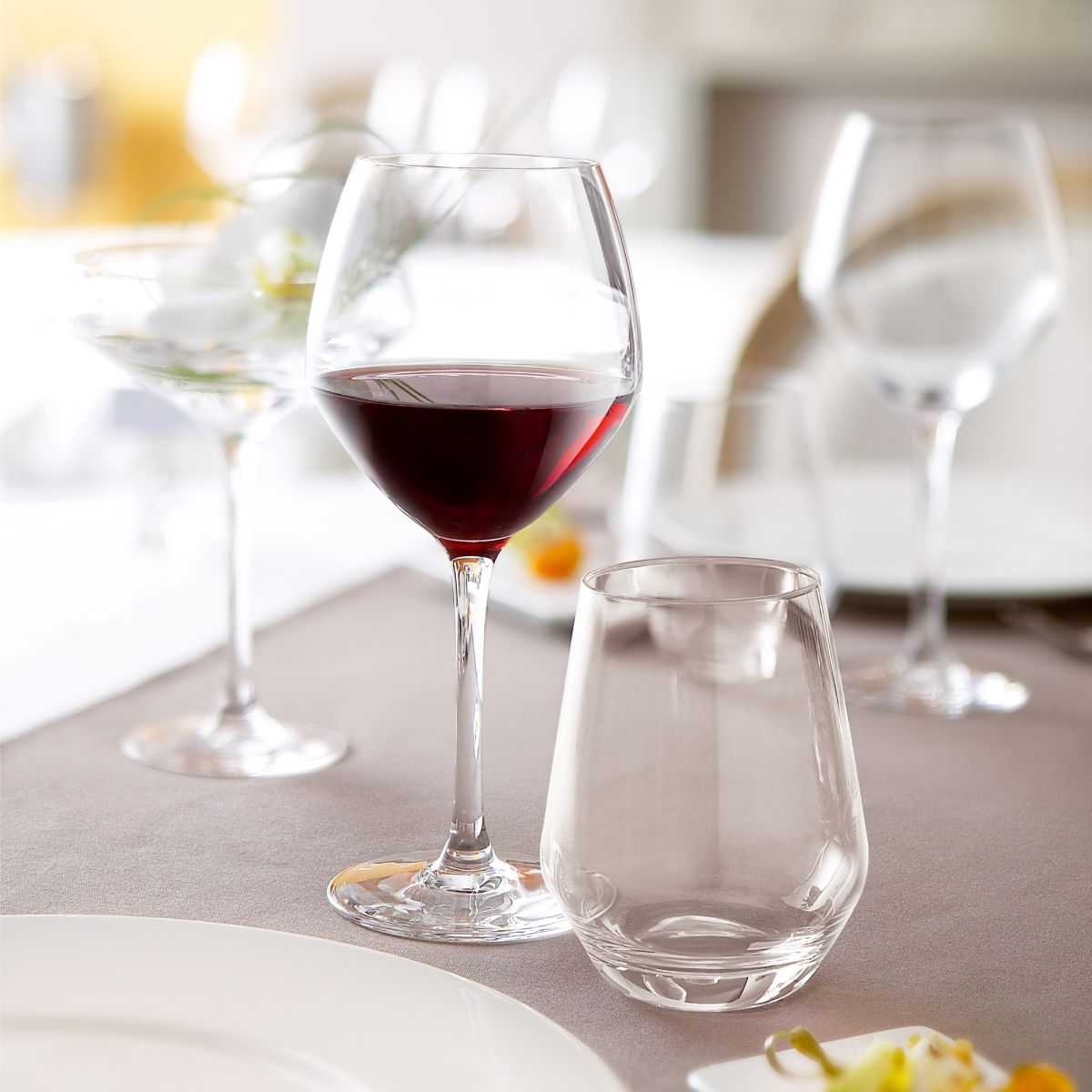 Gefülltes Cabernet-Jungweinglas 35 cl. präsentiert in warmer Umgebung auf dem Tisch.