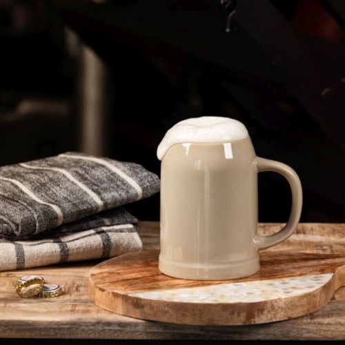 Bierkrug aus Steingut, 50 cl, gefüllt mit Bier, in stimmungsvollem Ambiente.