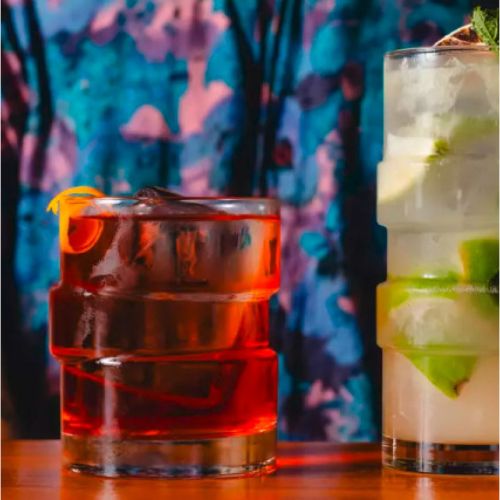 Das Glitch Becherglas 35,5 cl. mit Getränken gefüllt, in stimmungsvollem Ambiente platziert.