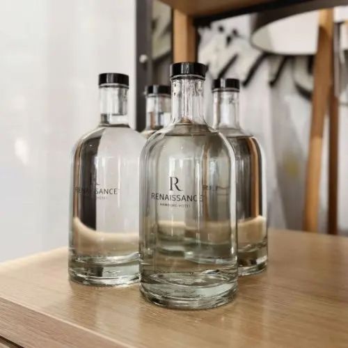 Gefüllte Flasche Oslo 0,7 Liter mit aufgedrucktem Logo in einem dekorierten Ambiente-Raum.