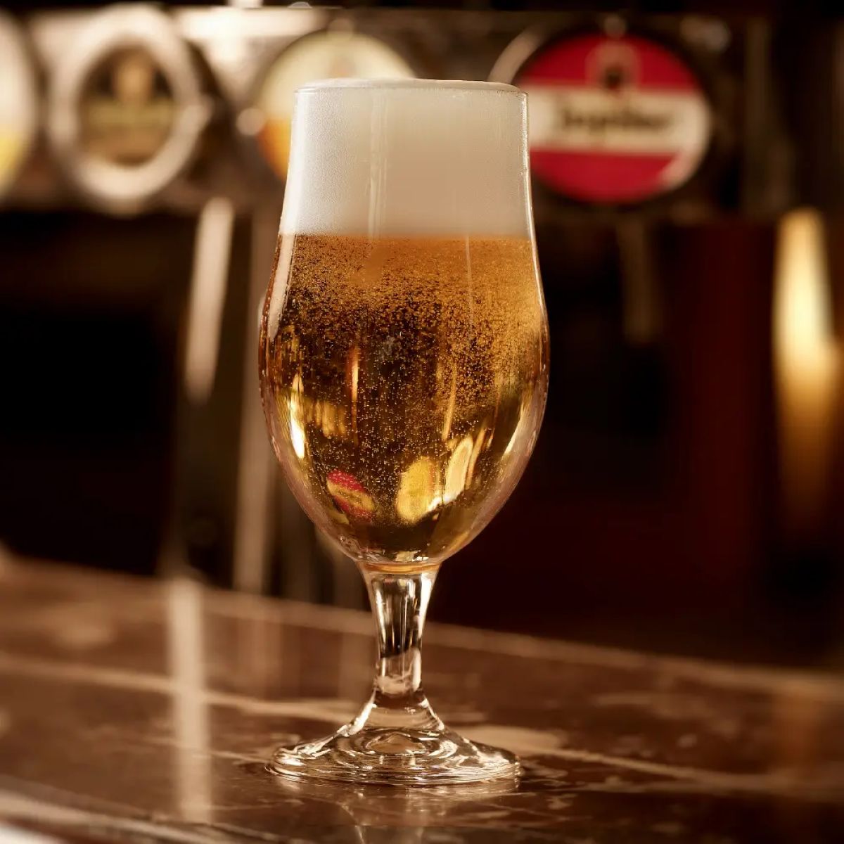 Bierglas Executive 26 cl. mit Bier gefüllt und auf Holztisch in stimmungsvoller Umgebung platziert.